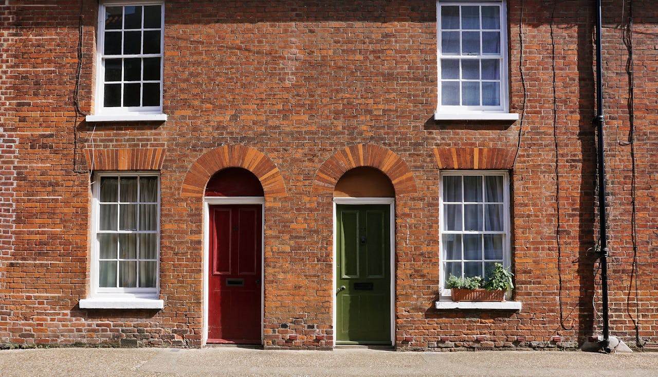 A vintage brick facade featuring red and green doors in an urban setting.