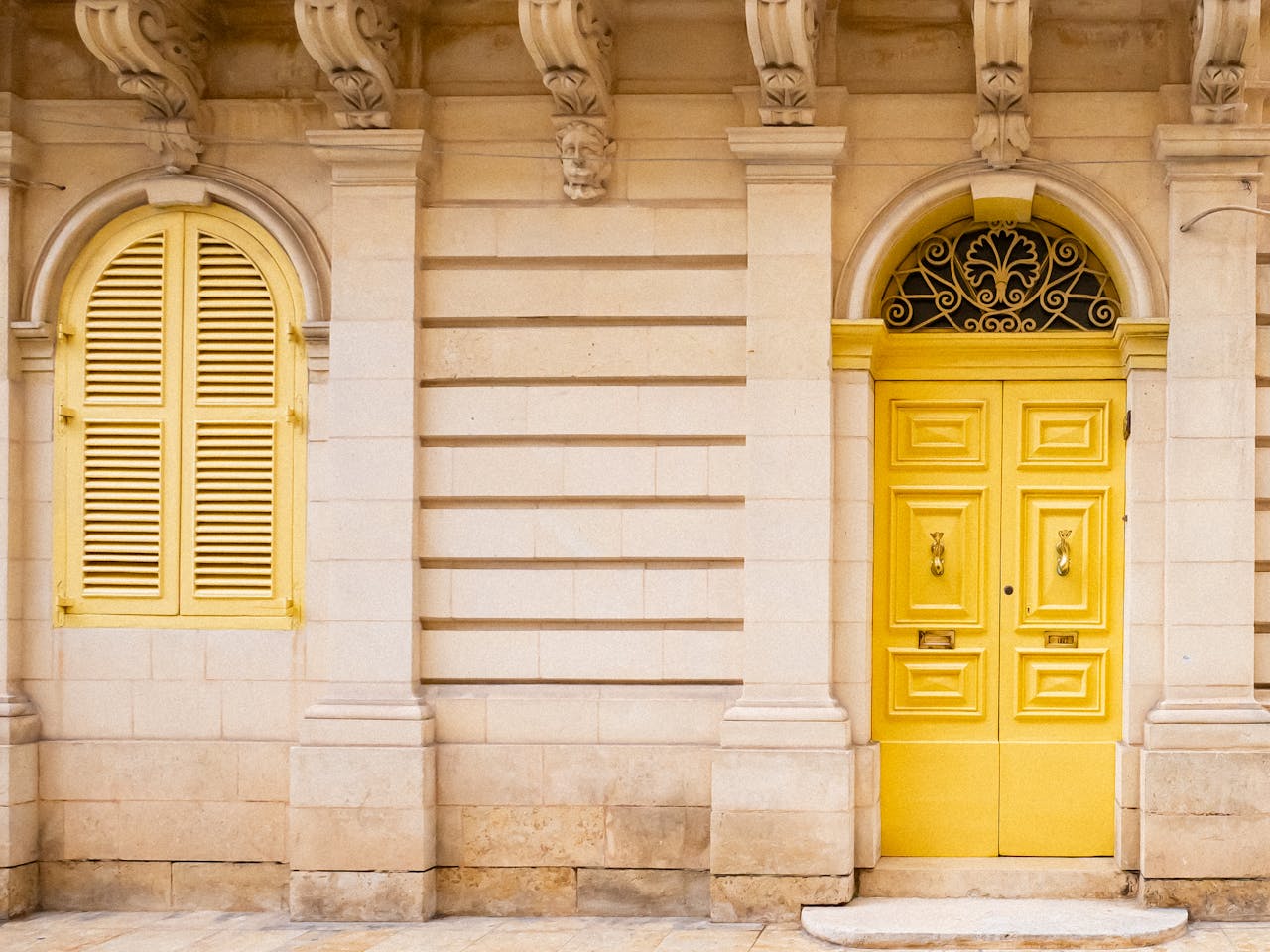 A charming architectural detail of a yellow door and window on a stone building facade.
