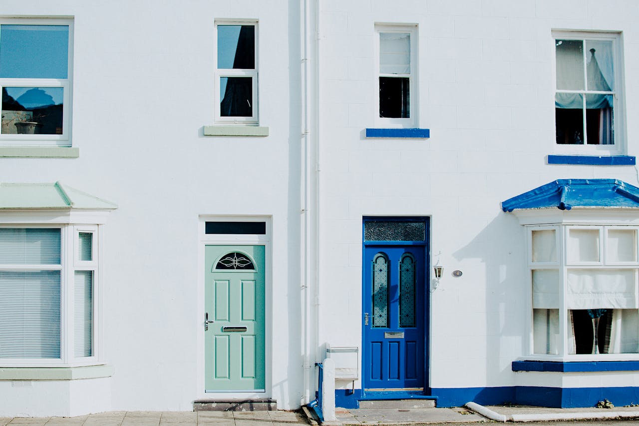 A modern exterior featuring a contrast of blue and green doors on a white building facade.